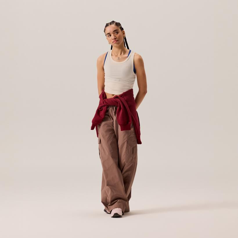 Woman posing in a studio background wearing New Balance apparel and 574 sneakers