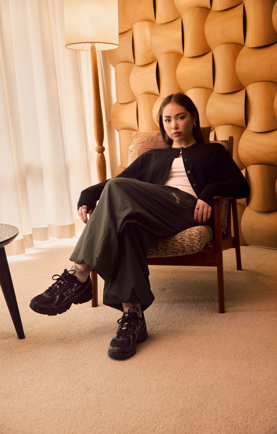 A woman sitting on a chair, wearing new balance 740 sneakers