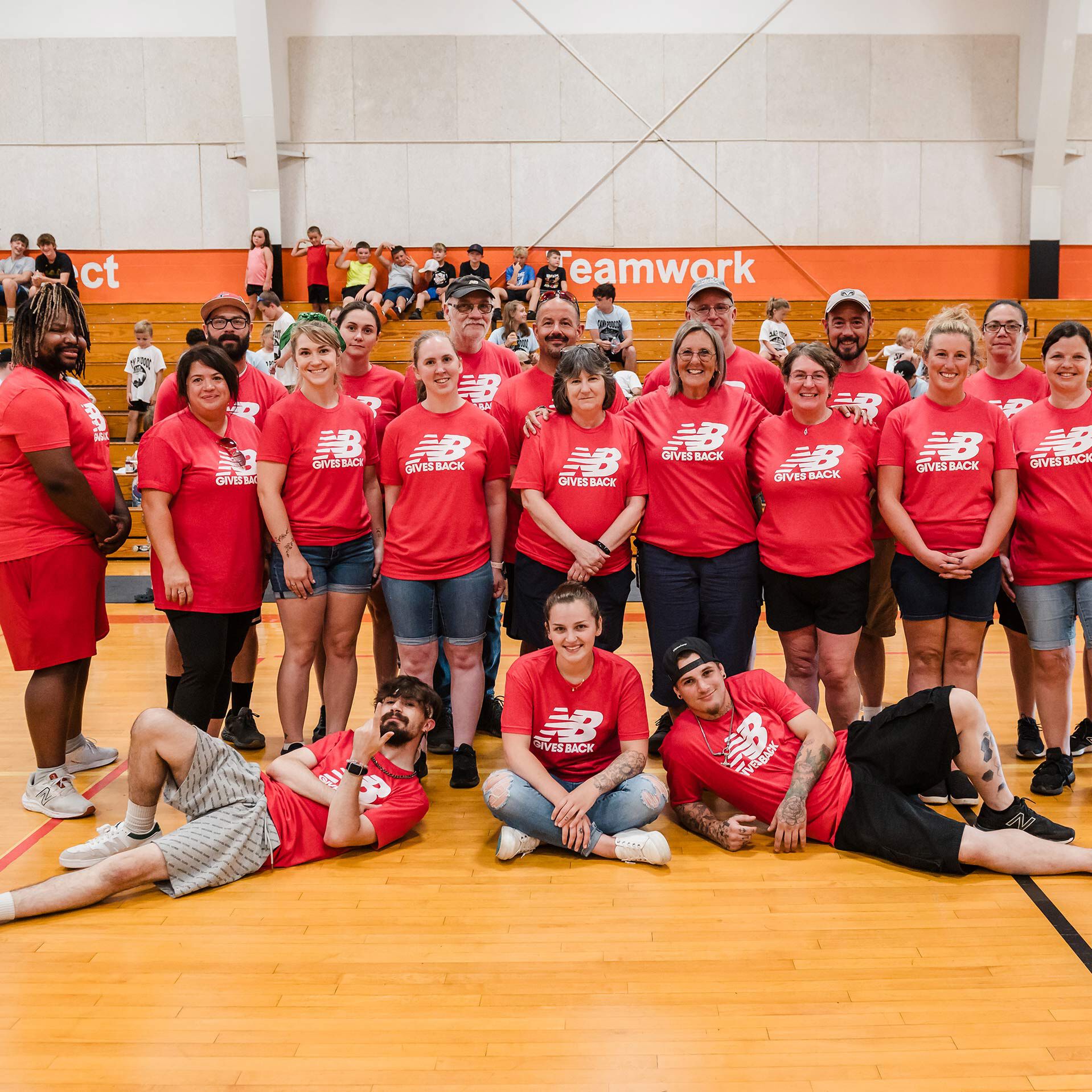 A group shot of 18 adult New Balance associate volunteers while onsite at a community event.