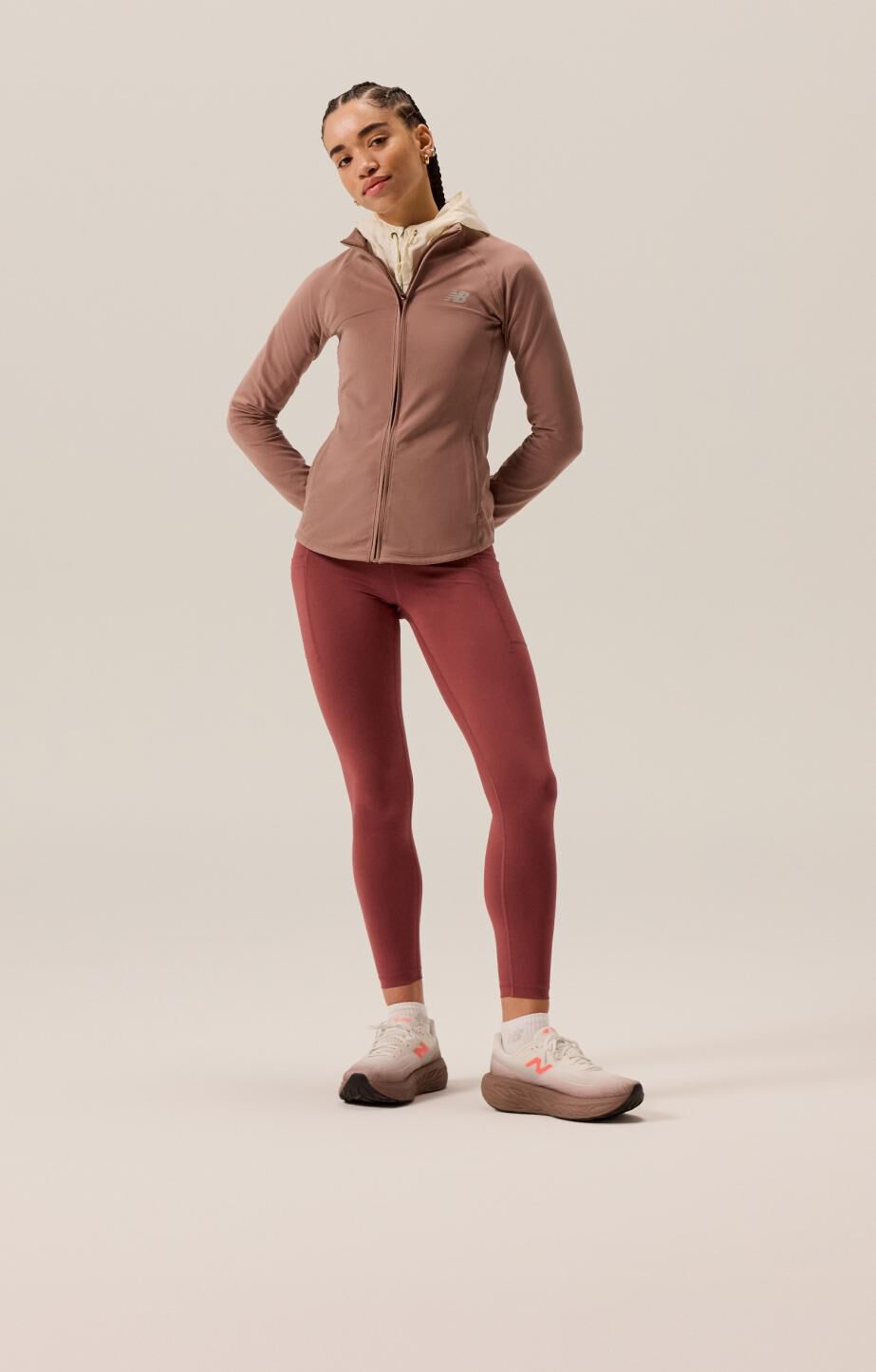 Lady wearing maroon tights and jacket in white and brown running shoes. 