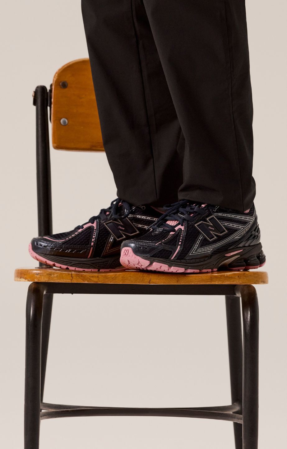 A person standing on a chair and wearing new balance 1906 sneakers