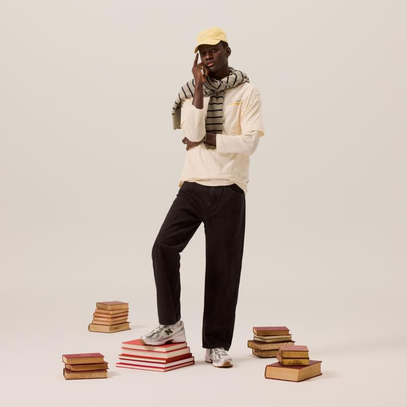 Man standing in a studio background surrounded by books wearing New Balance 740 sneakers