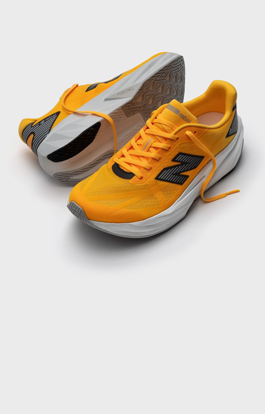 A pair of orange FuelCell Rebel shoes on a grey background. 