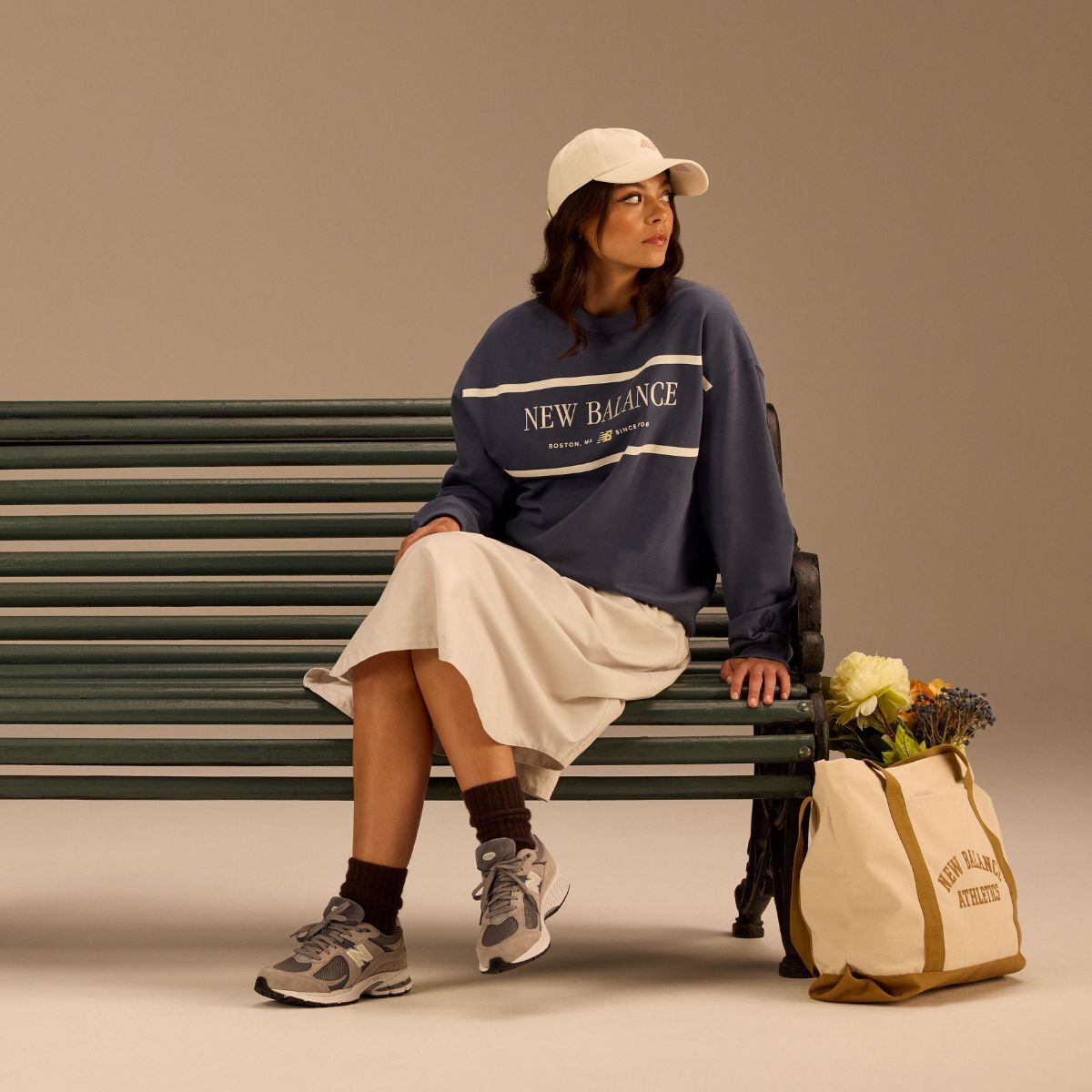 Woman sitting on a park bench wearing New Balance apparel and 2002 sneakers