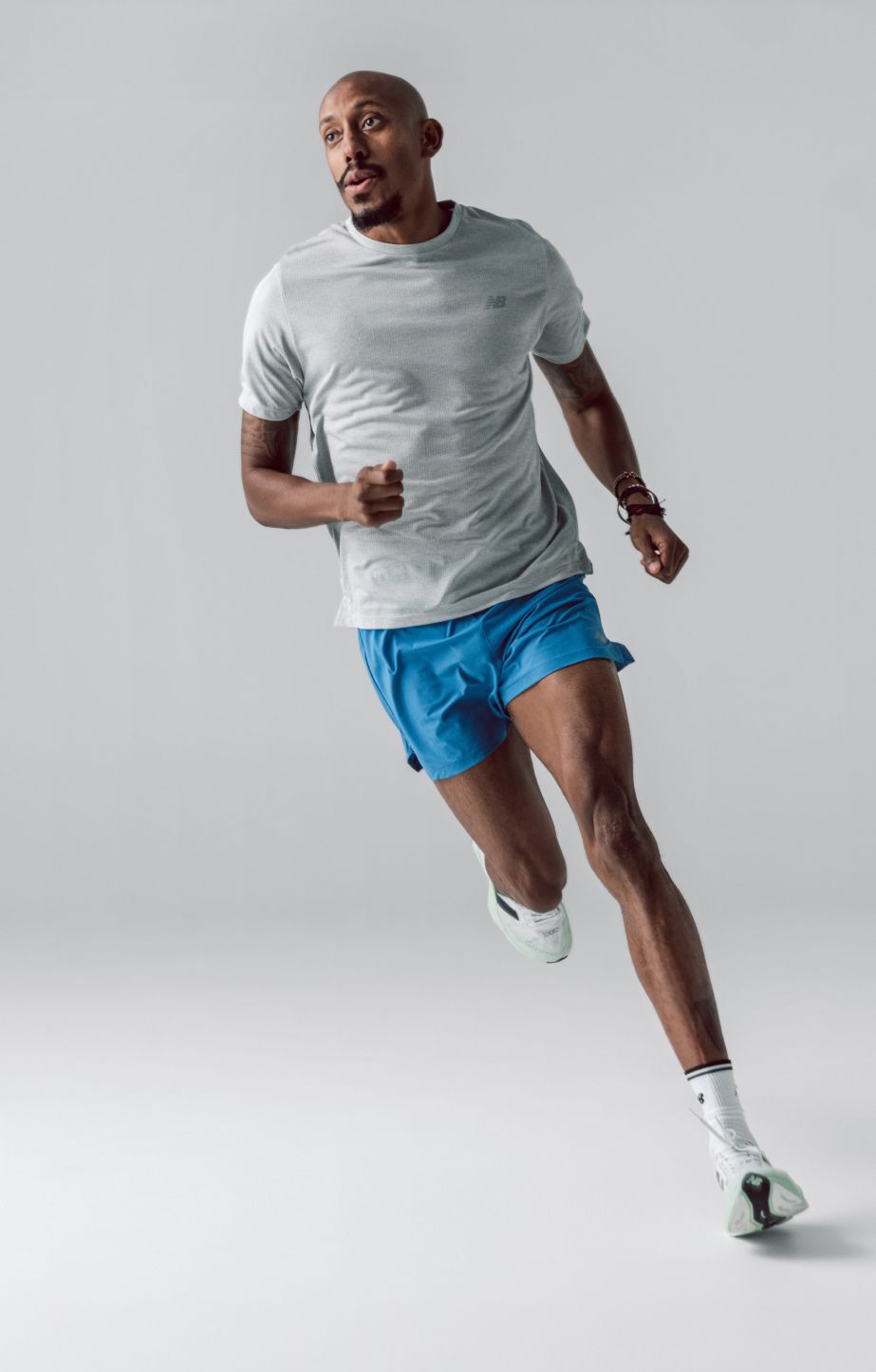 Young man running in blue short in front of a grey background. 