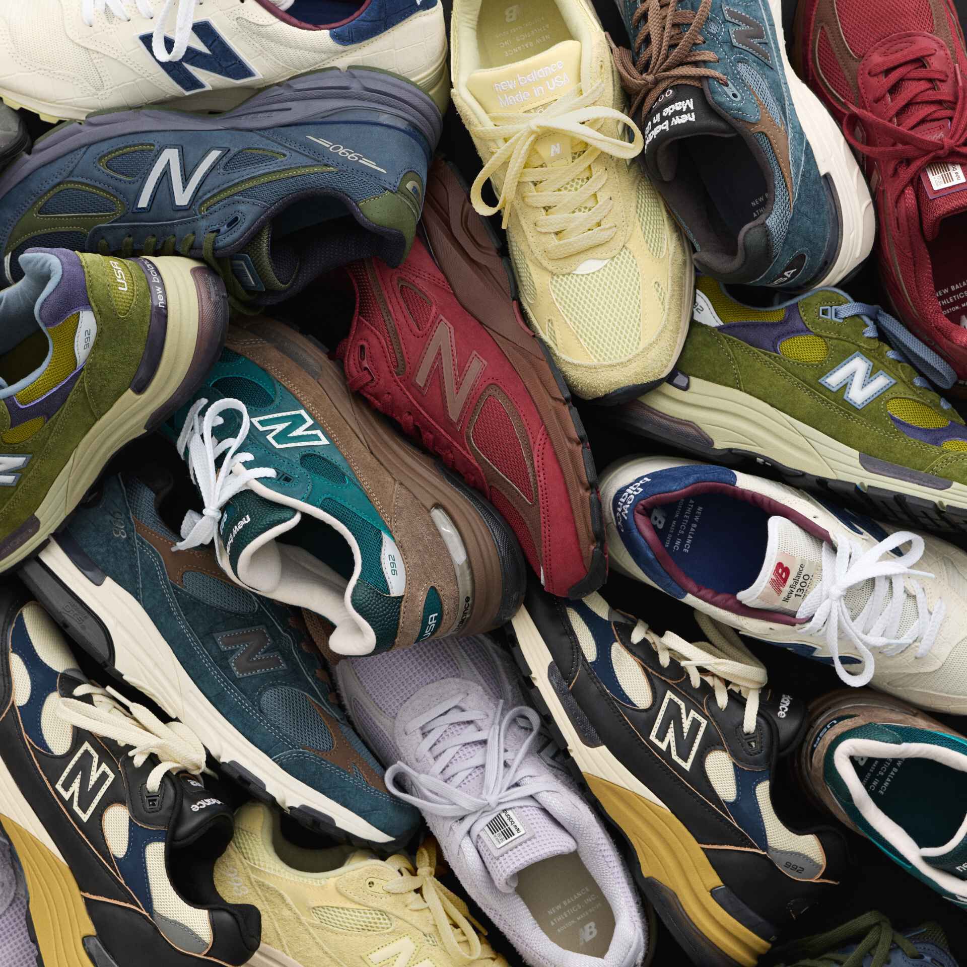 A top-down image of a pair of grey 990v6 sneakers on a grey studio backdrop. 