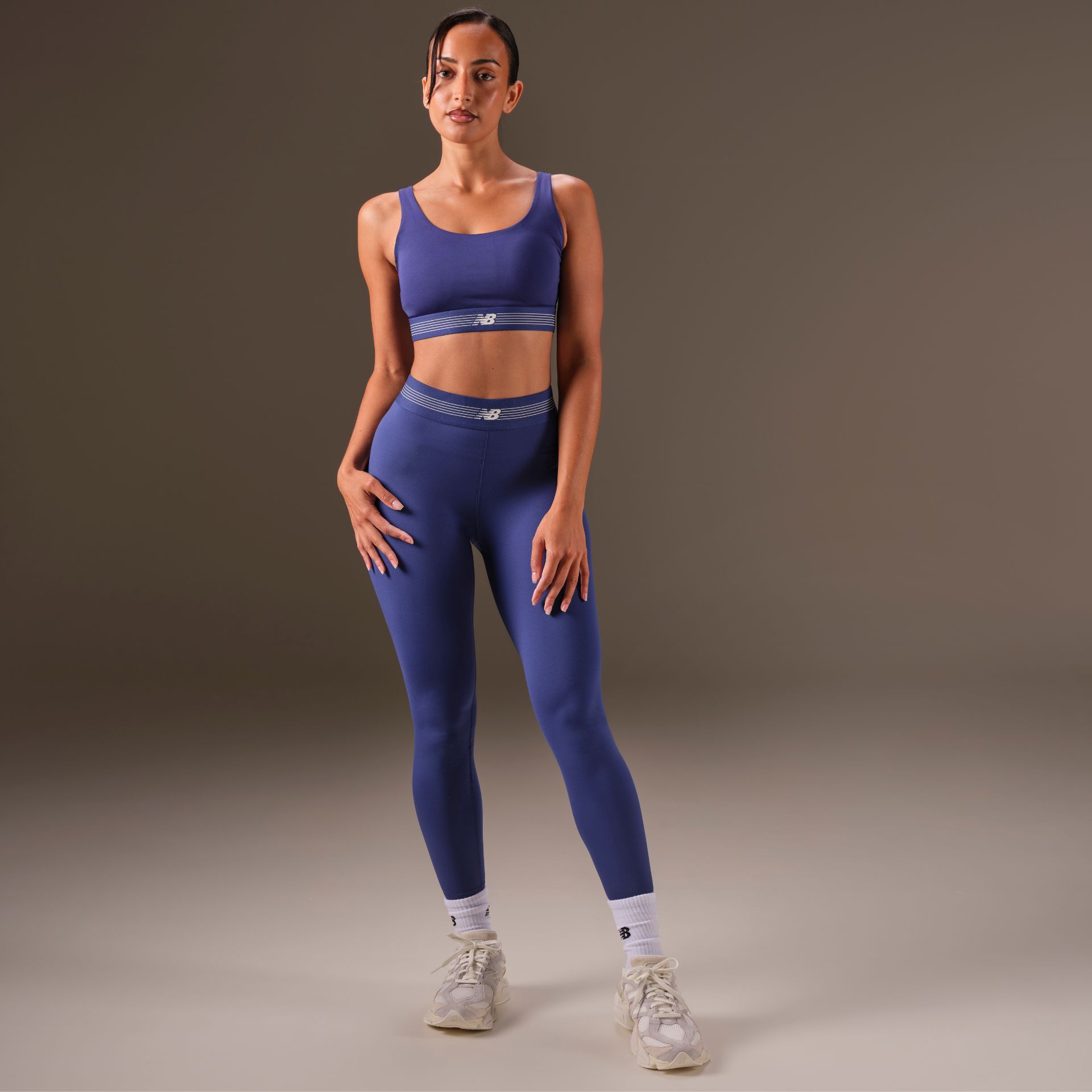 Woman in a studio background wearing 9060 sneakers and New Balance apparel