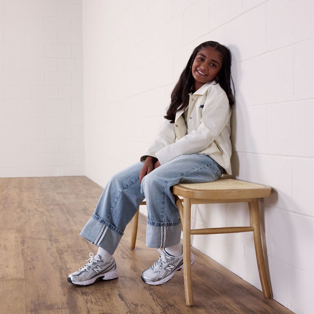 Young girl sitting on a bench wearing New Balance 740 sneakers