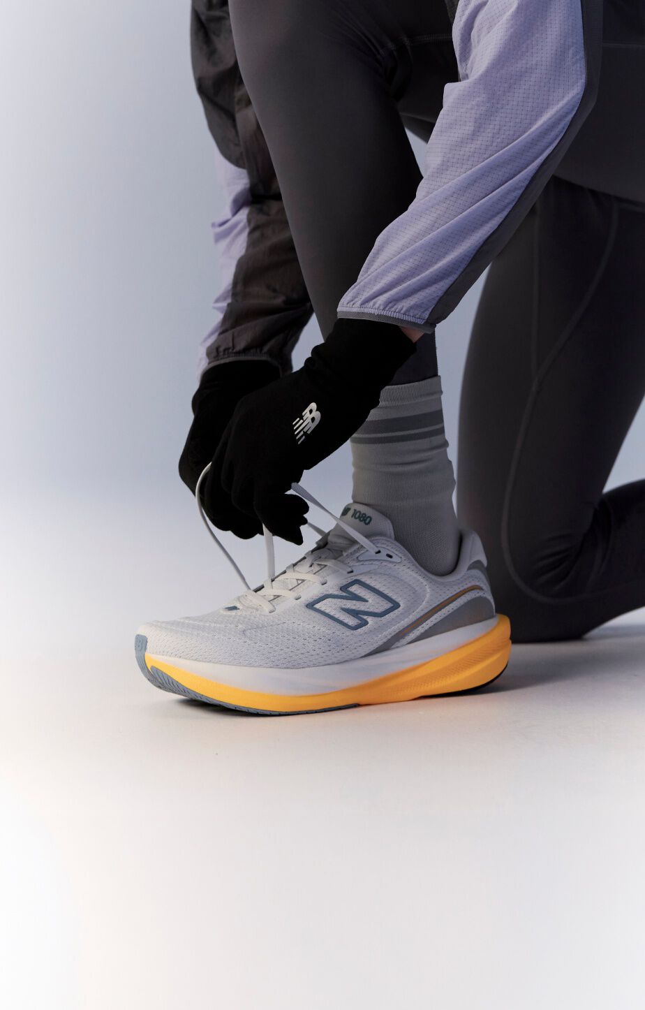 Knee down image of person tying a pair of 1080v15 running shoes 
